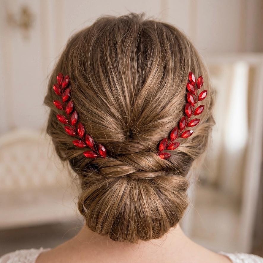 Rear view of a light brown braided bun with two vivid red leaf branches placed symmetrically and meeting above the center of the updo.
