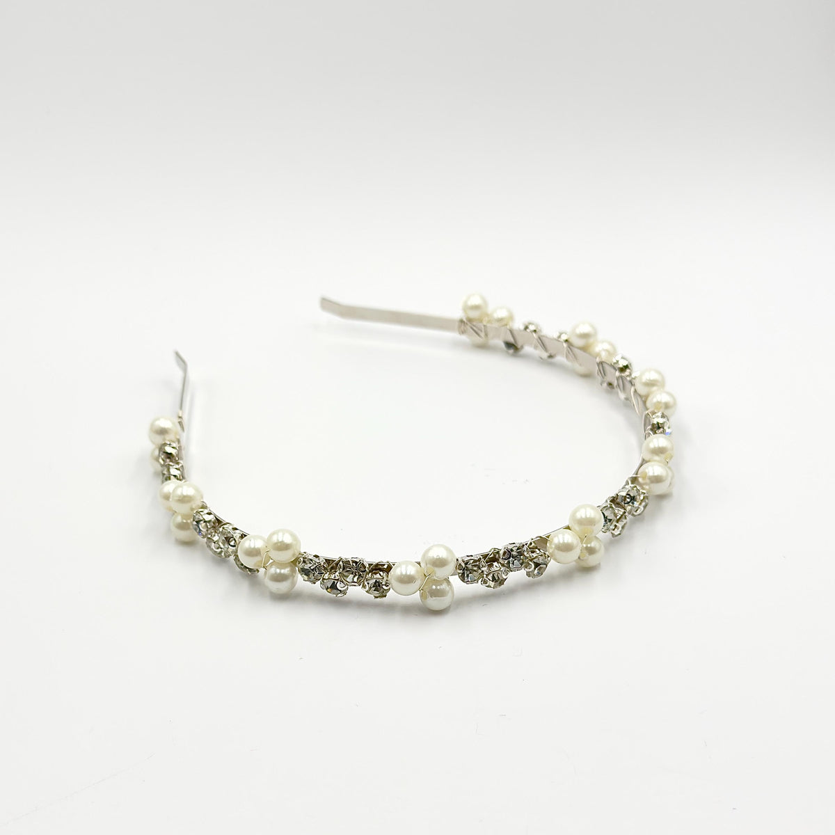 Bridal headband on a white background, photographed from a slightly angled front view, with a row of clear round stones and spaced groups of white pearls.