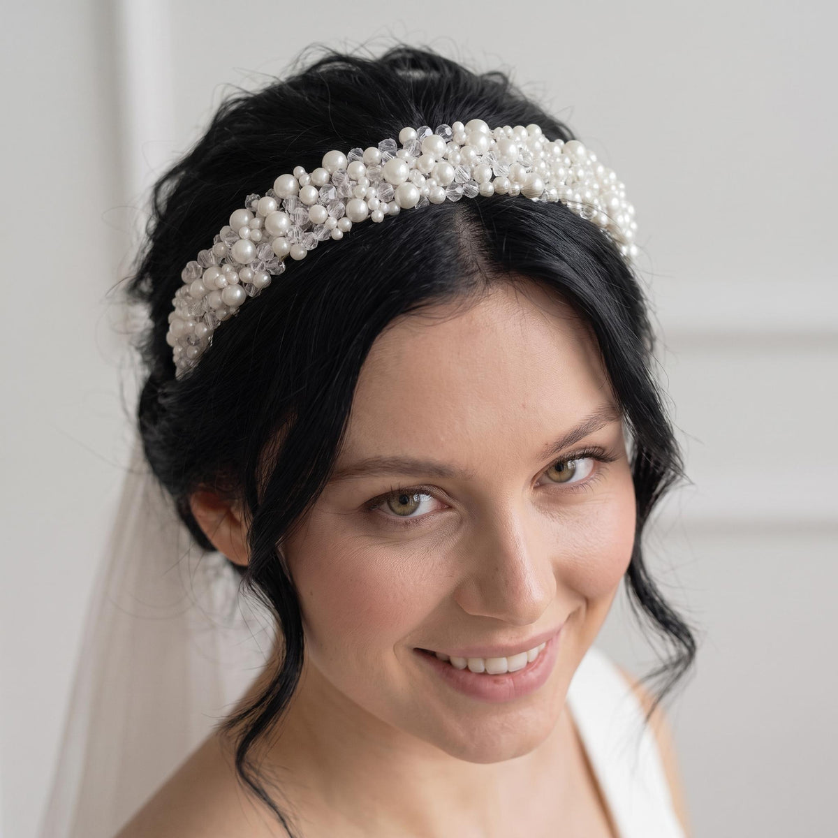 Required overhead view of the complete headband on a neutral background, showing its width, shape and balanced distribution of white pearls and clear crystals.