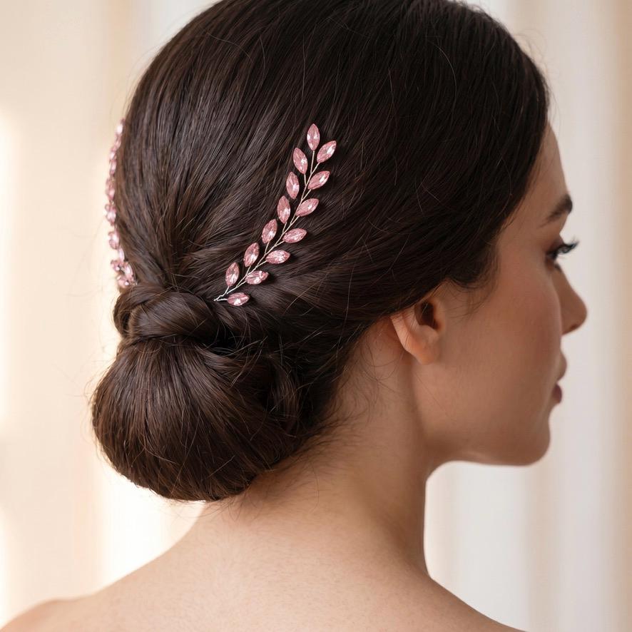 Rear view of a dark low bun with two pink faceted leaf branches placed symmetrically on the left and right sides above the hairstyle.