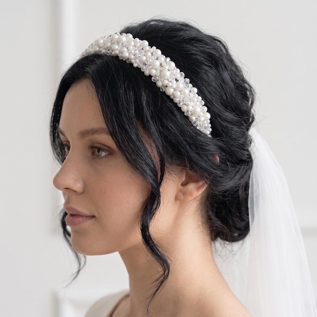 Wide bridal headband photographed from a slightly angled front view on a white background, layered with white pearls in varied sizes and clear round faceted crystal beads.